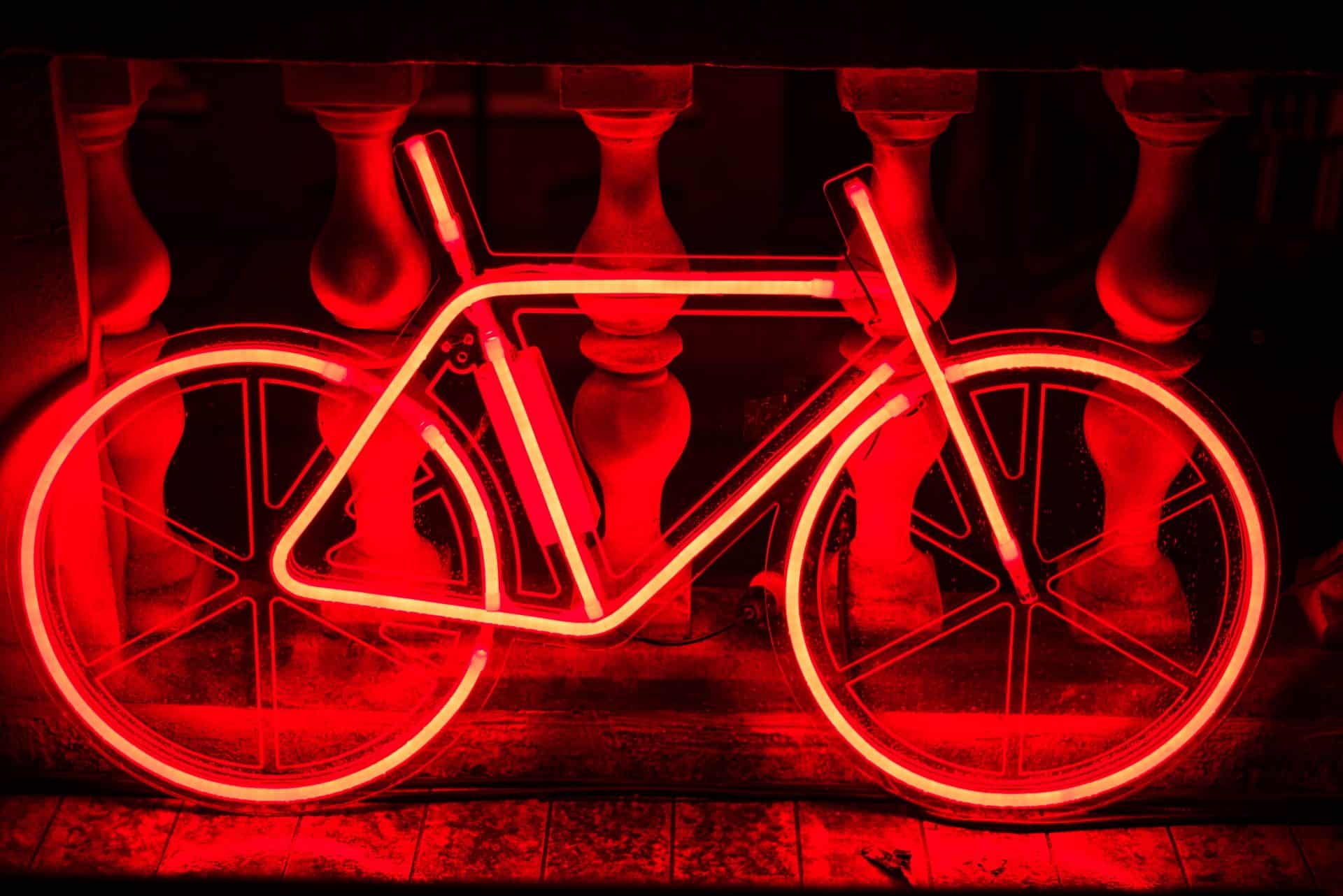 Œuvre d'art en forme de vélo éclairée avec des néons rouges dans la nuit