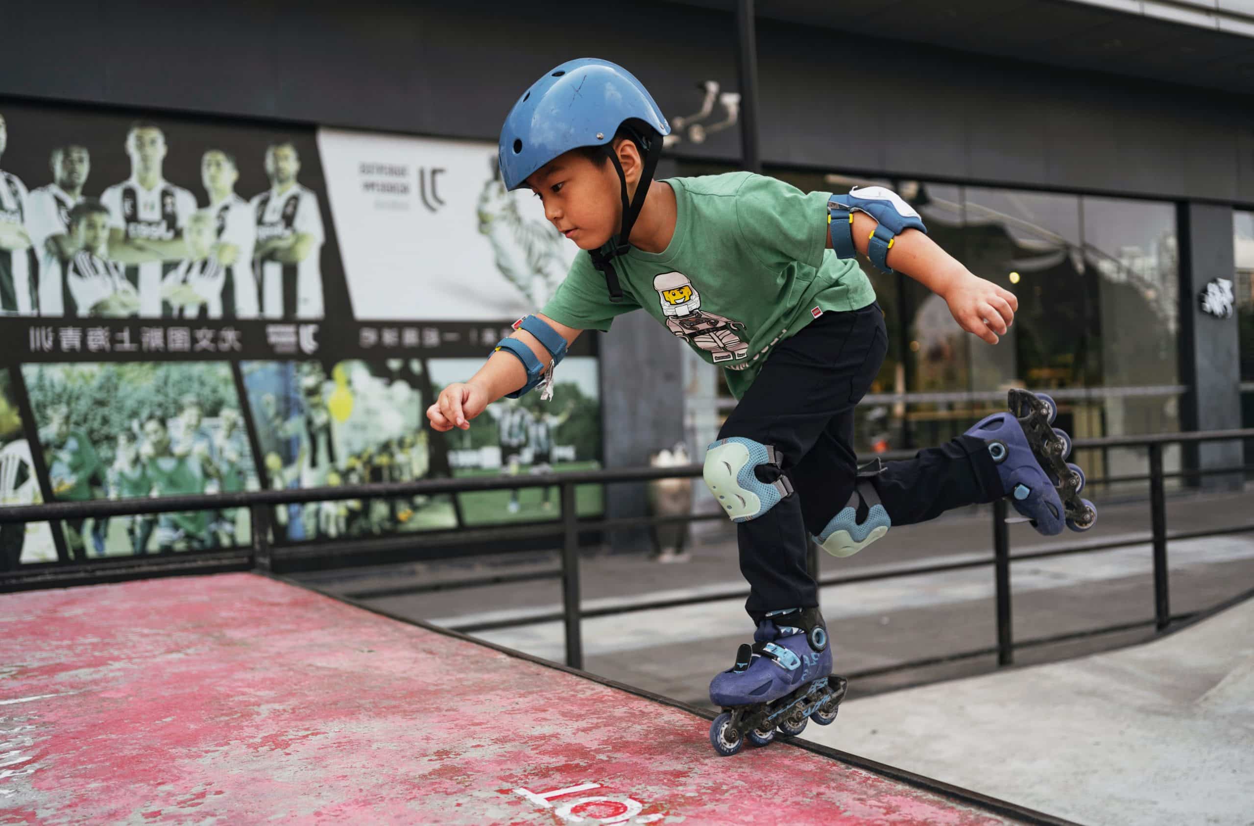 jeune garçon faisant du roller avec des protections (casque, genouillère et coudière) dans un skatepark