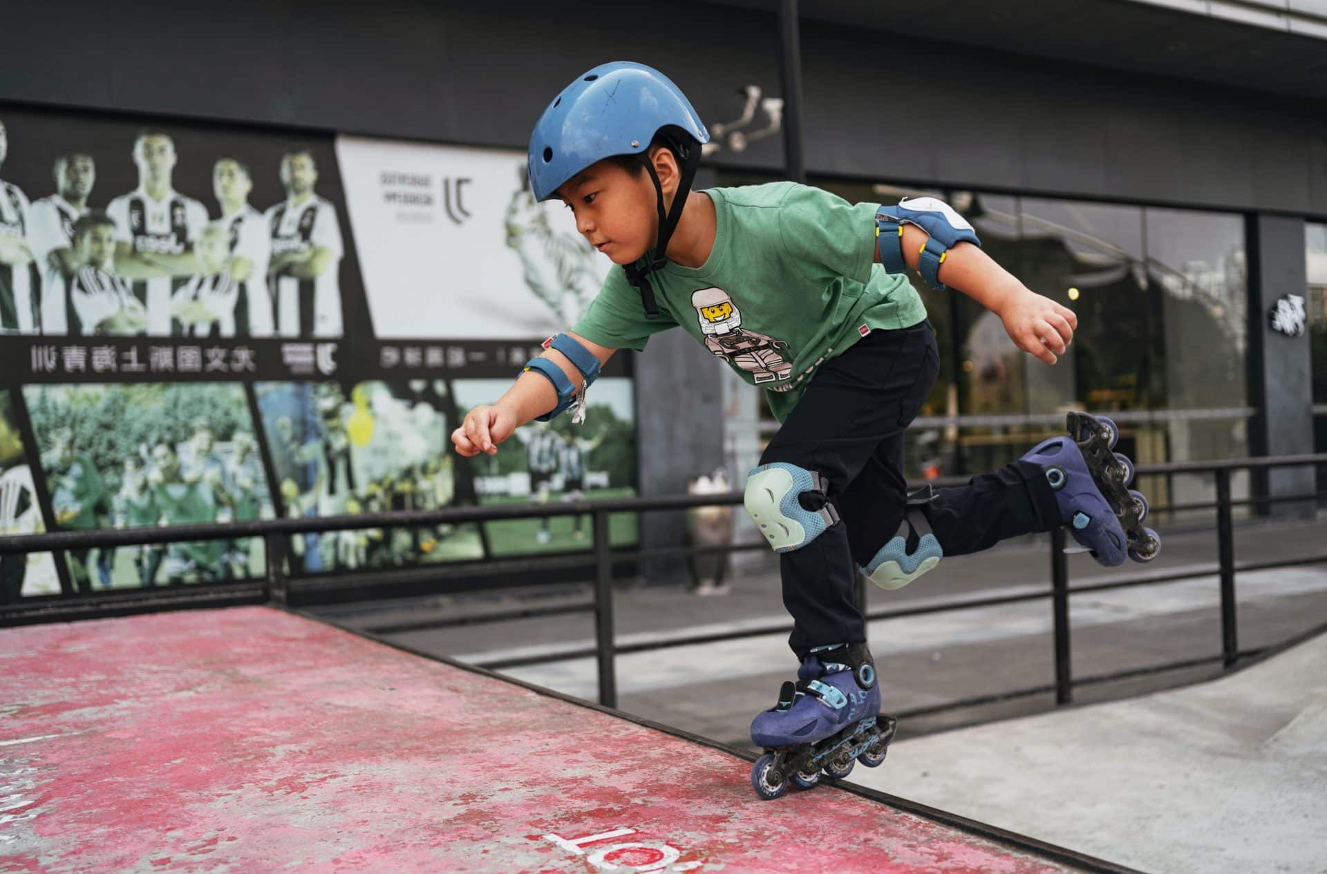 jeune garçon faisant du roller avec des protections (casque, genouillère et coudière) dans un skatepark