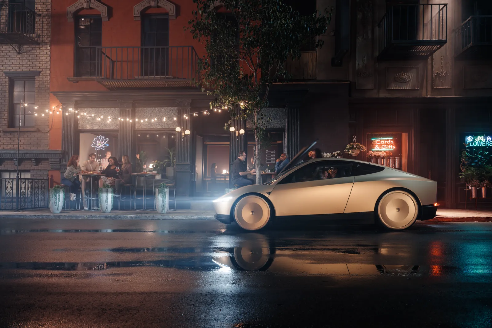 Tesla Cybercab passant de nuit devant une terrasse de café garnie de guirlandes lumineuses.