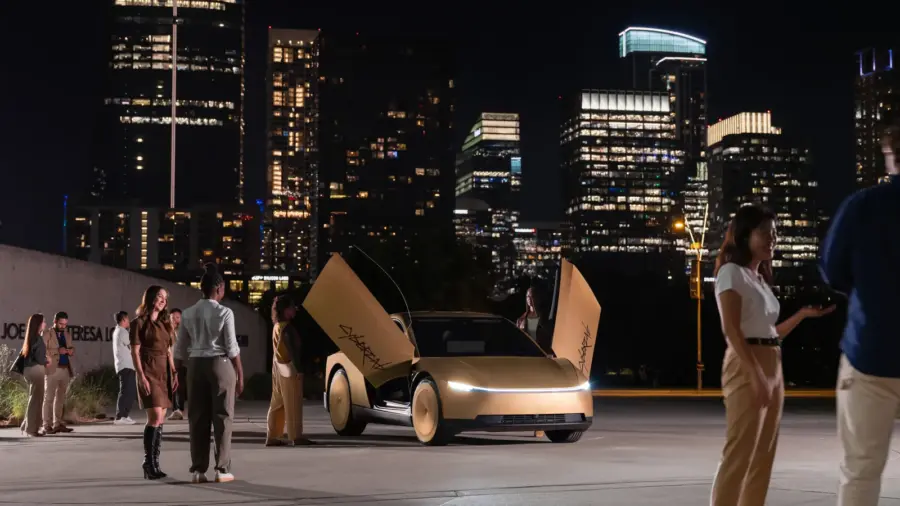 Plusieurs Tesla Cybercab dorés portes papillon relevées, de nuit, devant la ligne d’immeubles éclairés du centre d’Austin.